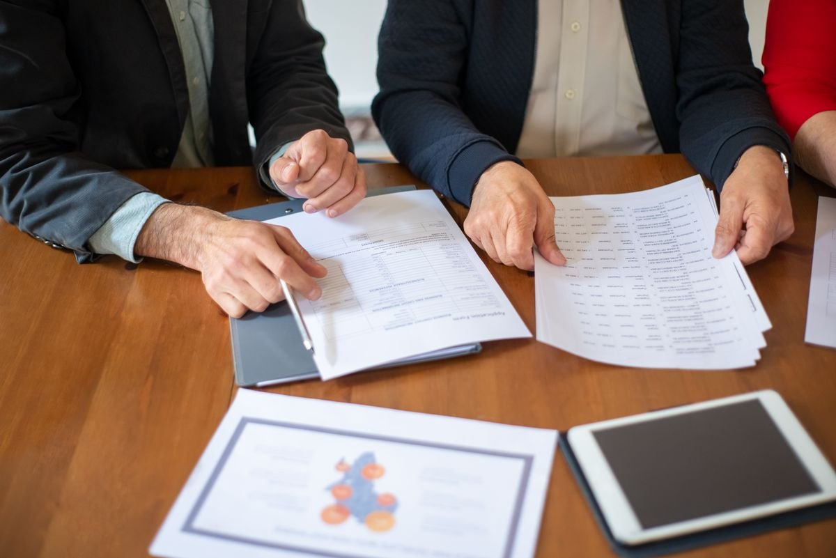 Consultants reviewing printed process documents and records at a meeting table
