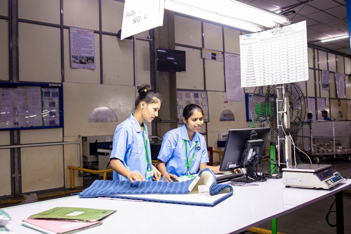 Two quality inspectors reviewing material and records at a factory inspection station