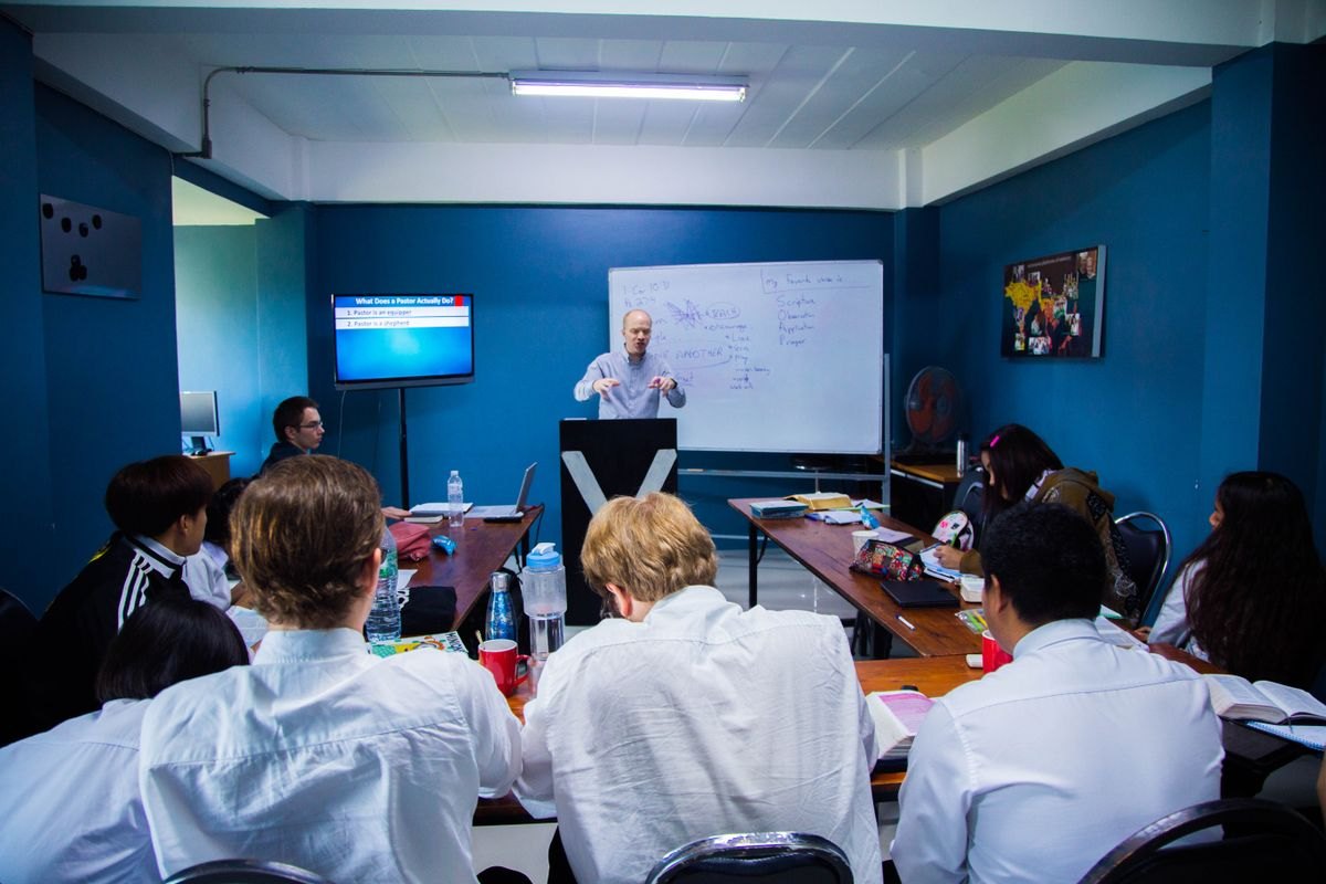 Instructor at a whiteboard leading a classroom session for adult learners