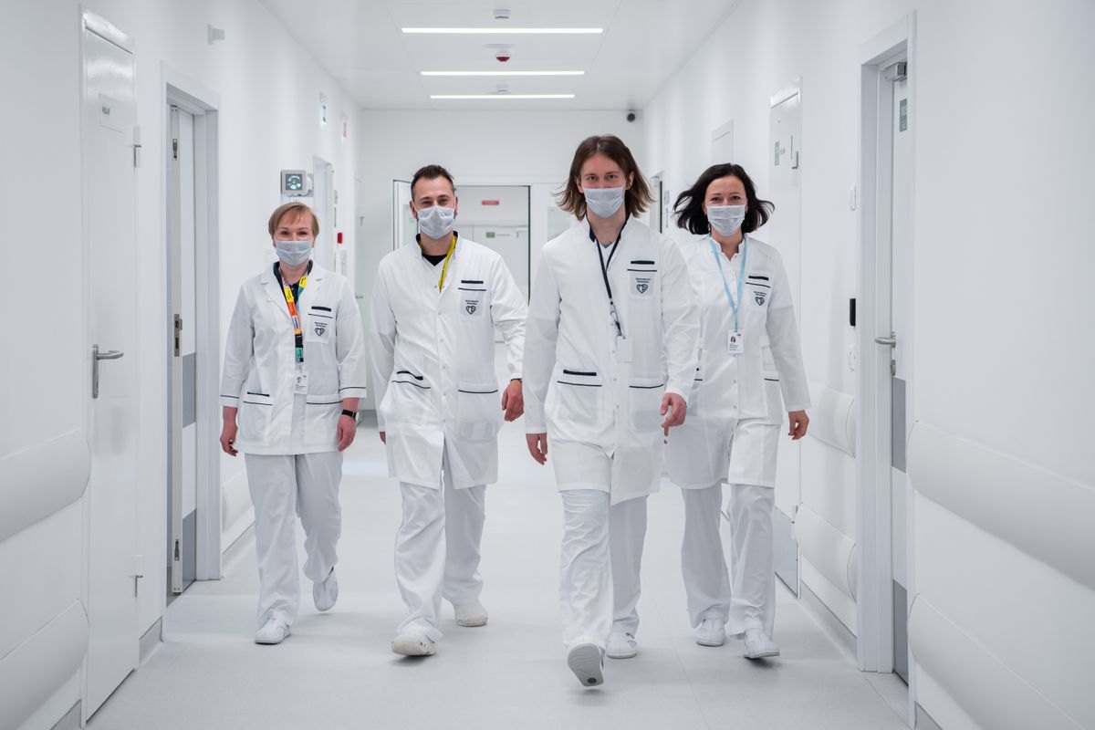 Clinical staff in white coats walking through a hospital corridor