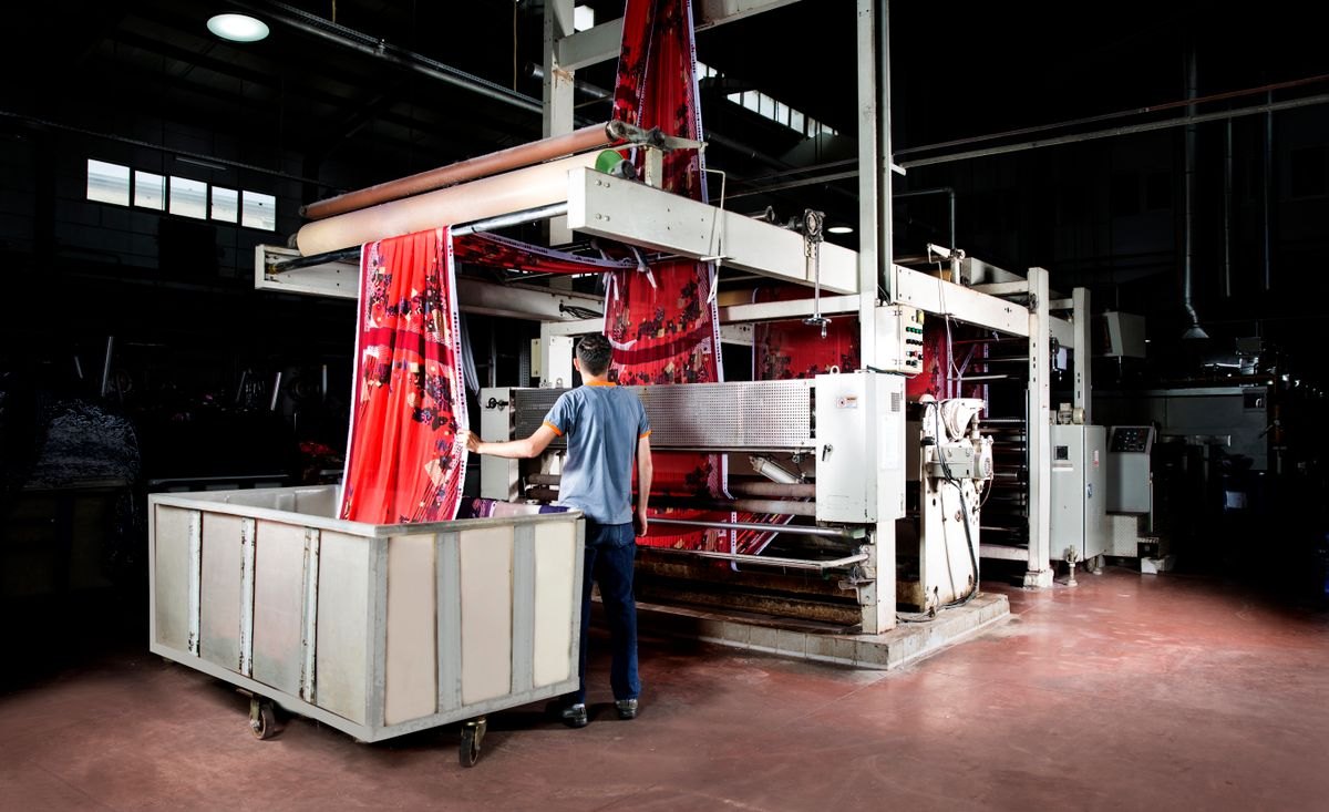 Industrial production floor with process equipment and an operator at work